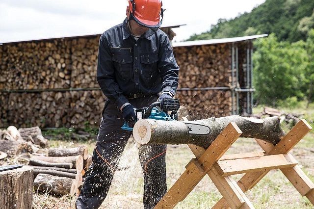 cutting log using a chainsaw while holding it on a bench